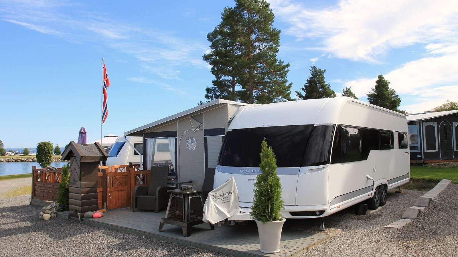 Velholdt campingvogn med spikertelt og platting på en campingplass