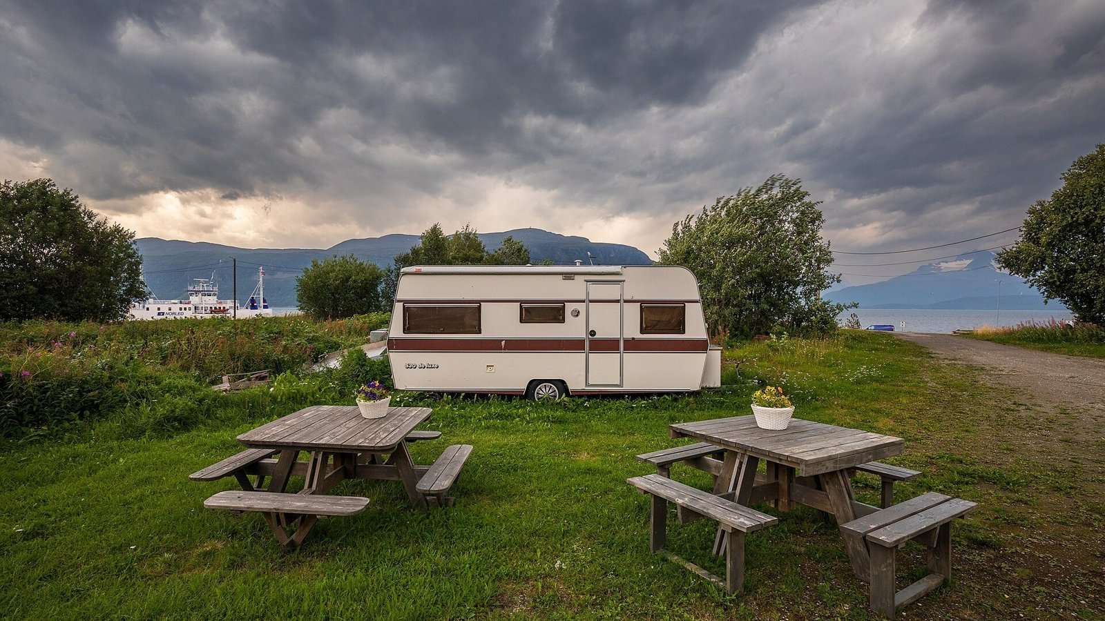 Eldre campingvogn under mørke regnskyer i Olderdalen
